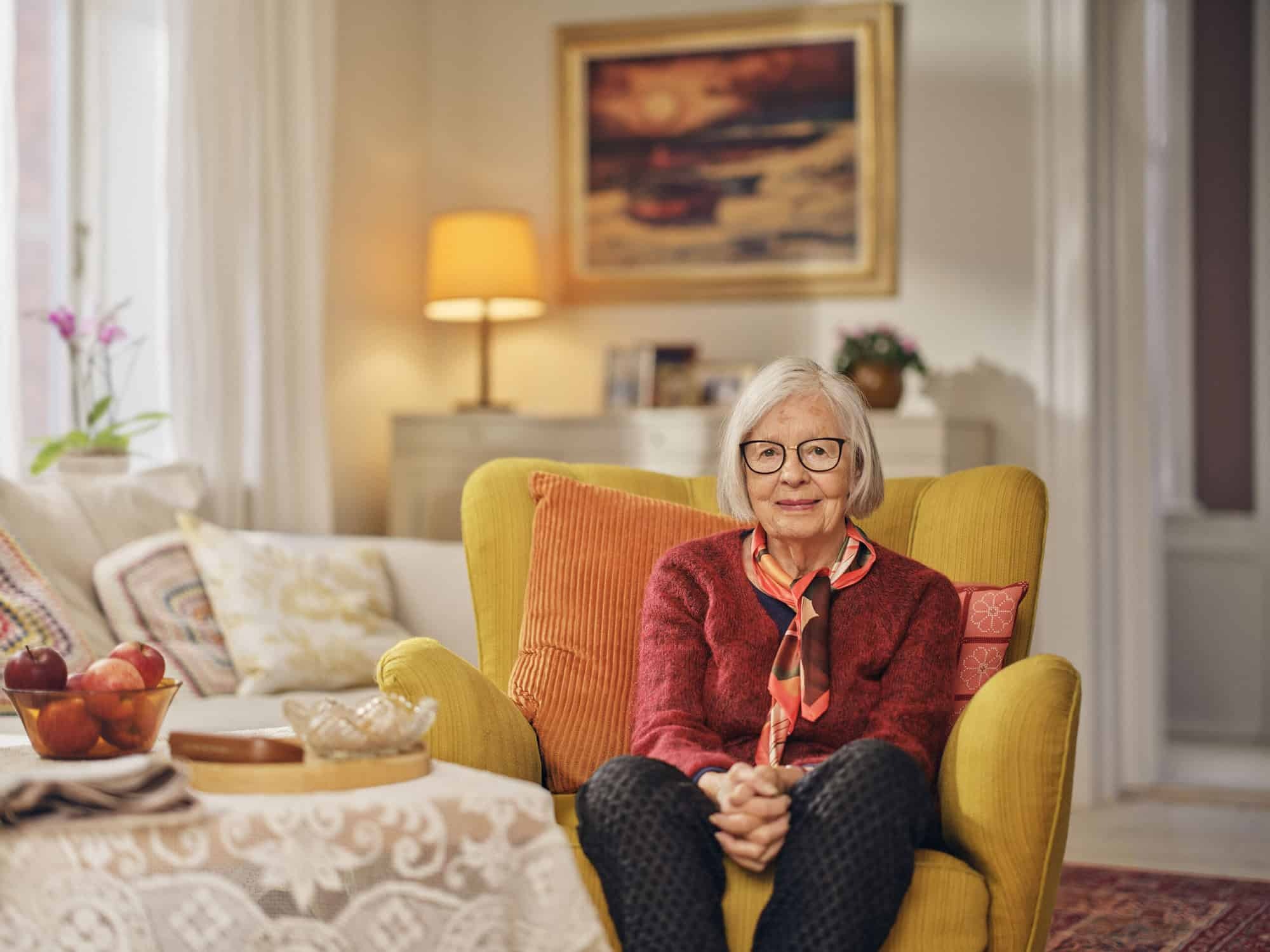 Smiling older woman sitting comfortably in a cozy living room 